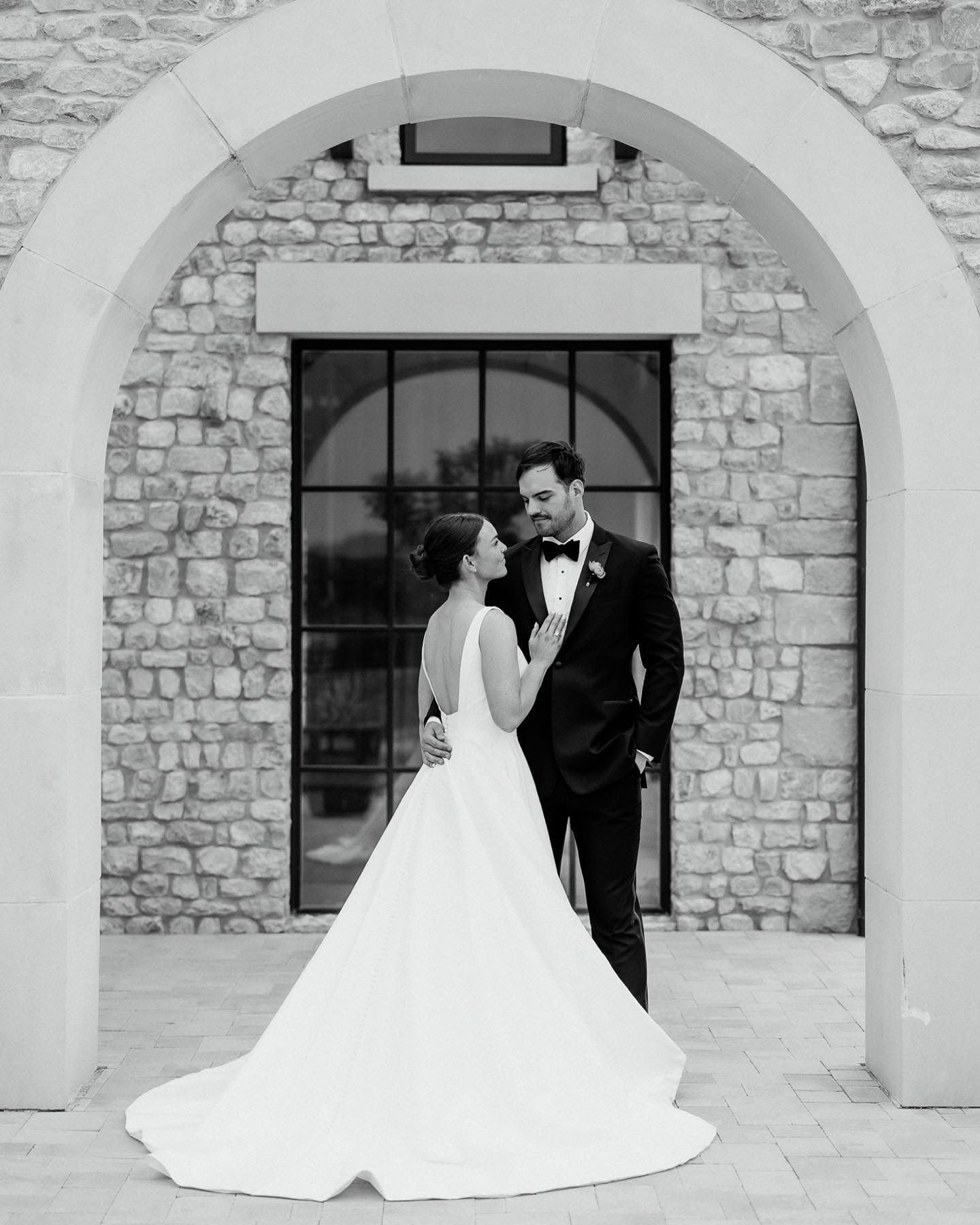 a black and white image of a wedding couple posing in front of a arch gateway