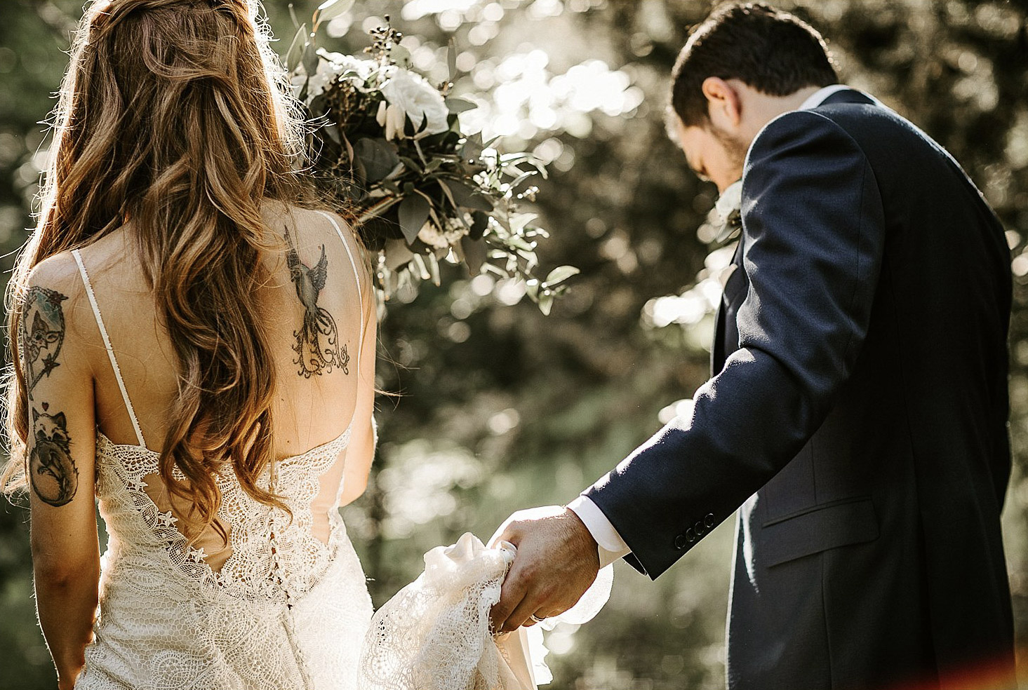 a groom managing the bridal dress while the bride is holding the bridal bouquet