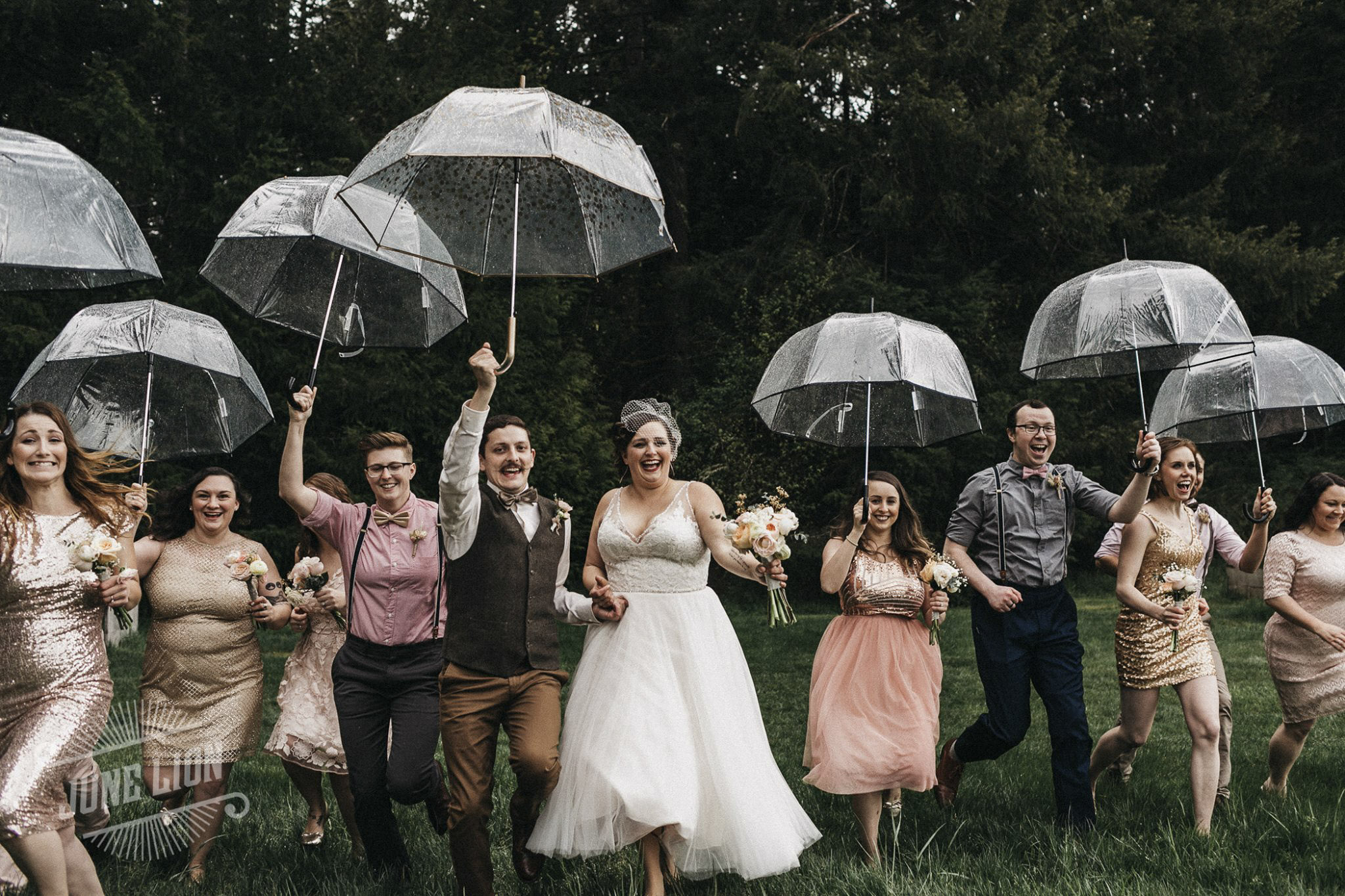 the bridesmaids, the groomsmen and the wedding couple is running holding umbrellas