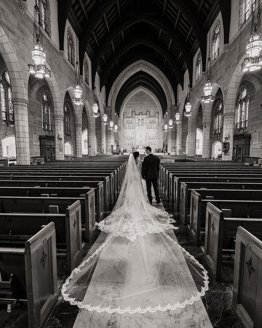 a couple walking down the aisle while the bridal dress trails behind her beautifully