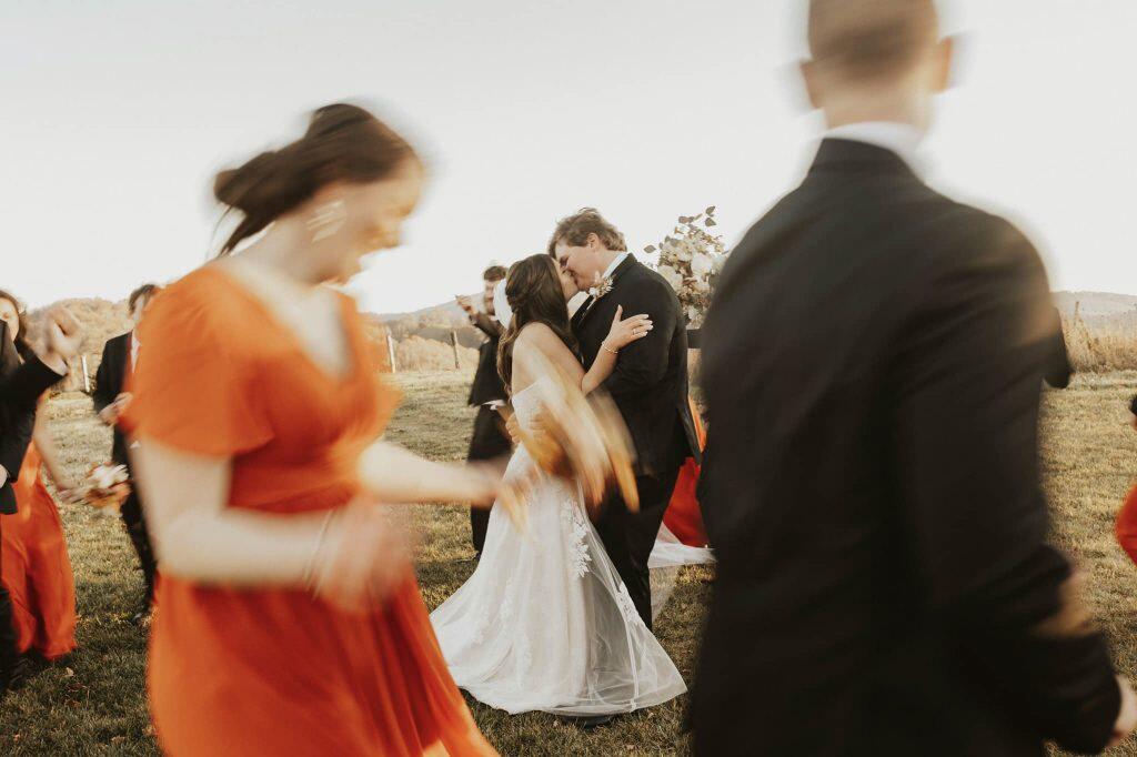 a couple kissing in the middle while their friends roam around them in a circle