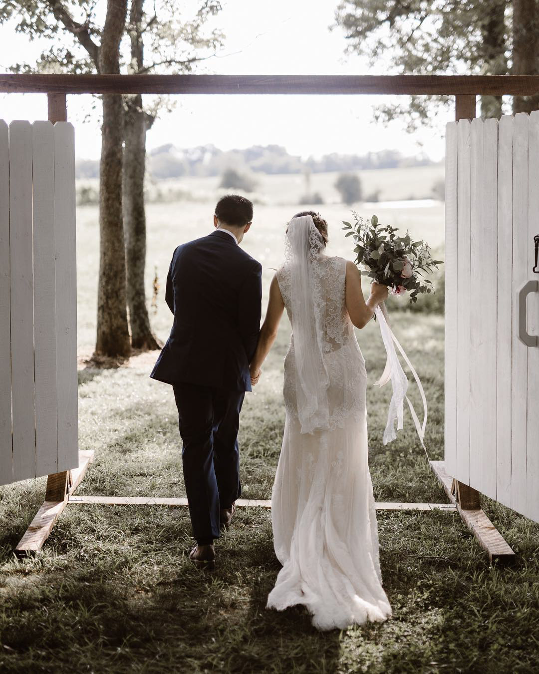 a wedding couple holding hands walking through a door