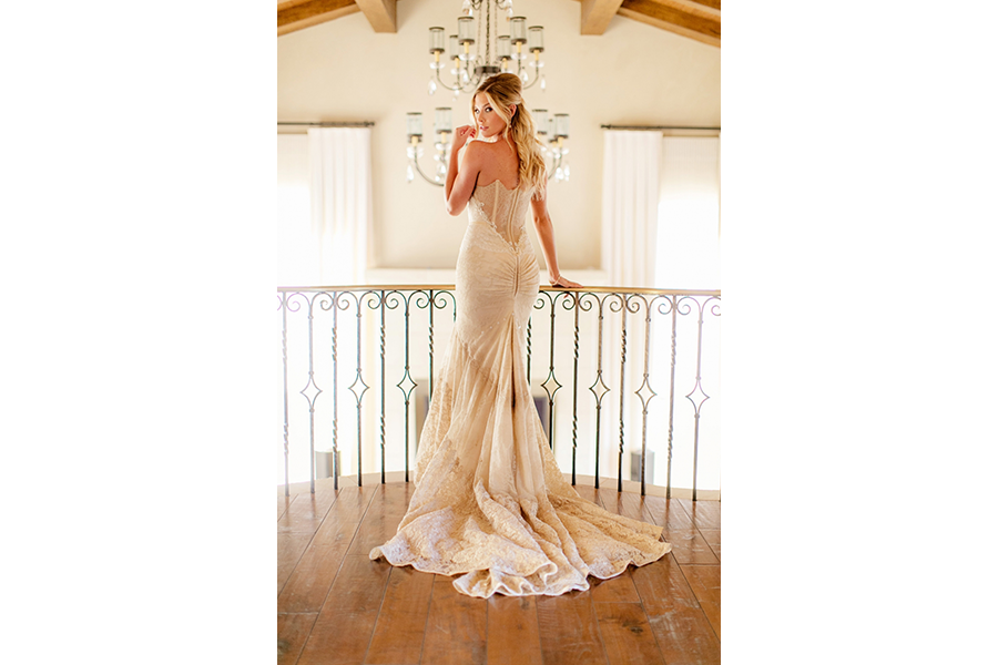 A solo shot of the bride as she stands facing away from the camera and turning her head back. 