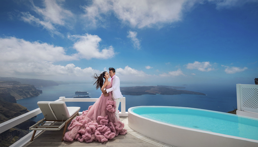 A couple posing beside a pool at a balcony overlooking the sea