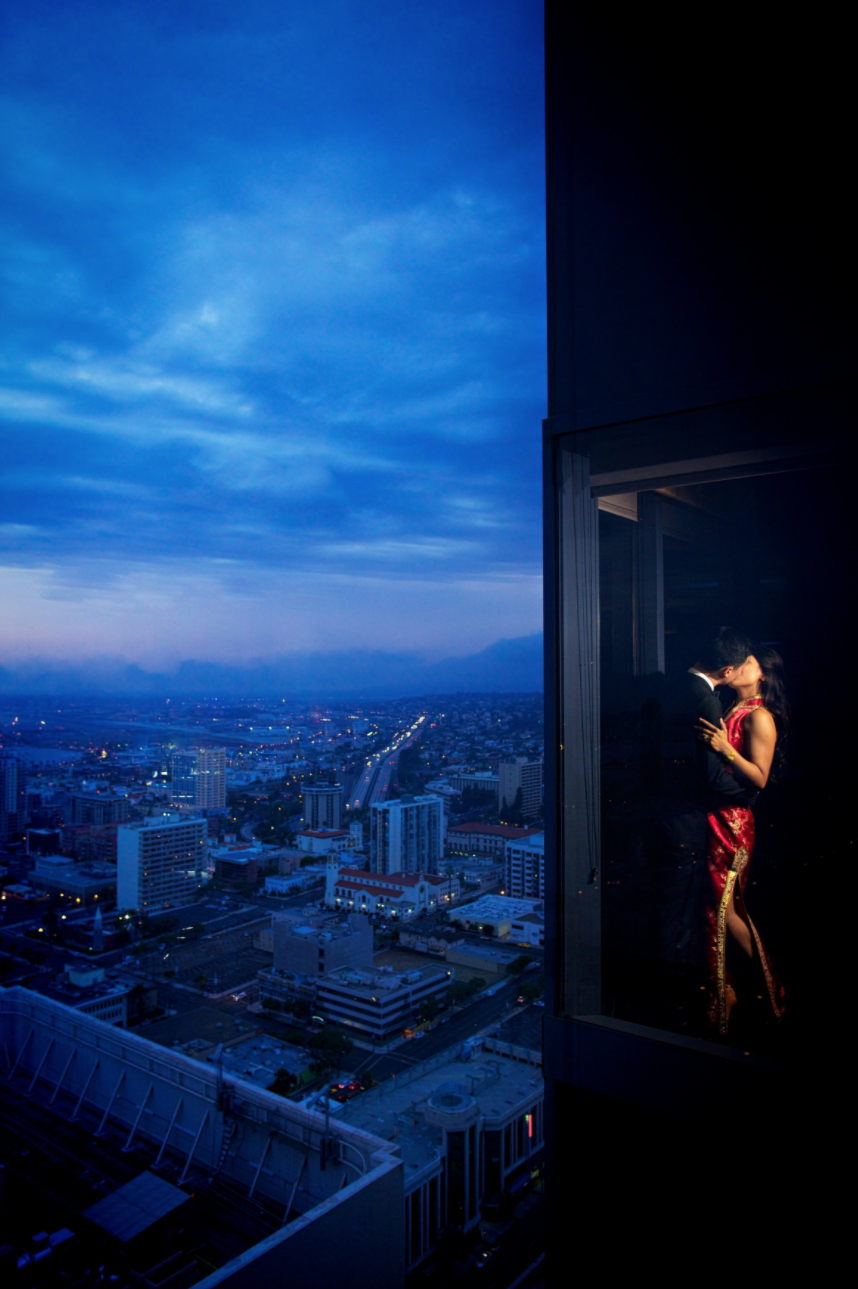 man and woman in window kissing with city view in the background