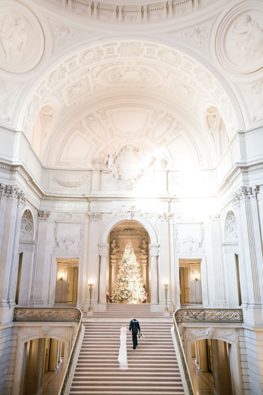 man and woman walking up stairs at san francisco courthouse with a Christmas tree 