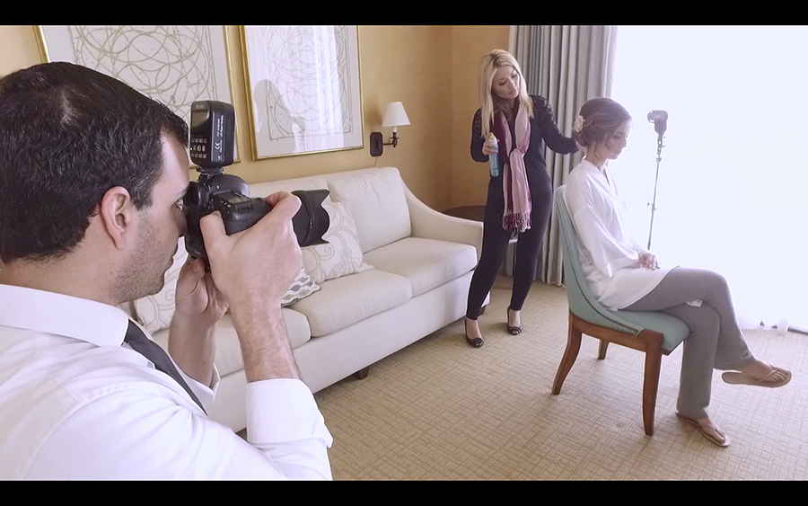 Over the shoulder shot of a photographer photographing a bride with her hairstylist in an off camera flash setup